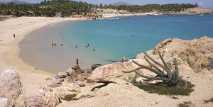 a group of people sitting on a rock near the ocean