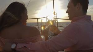 a couple toasting with a wine glass on a boat during sunset