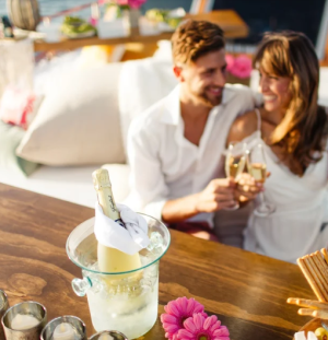 a couple sitting at a table eating food and drinking
