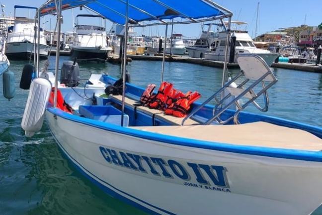 Small white and blue boat named 'CHAYITO IV' docked in a harbor with life jackets on seats.