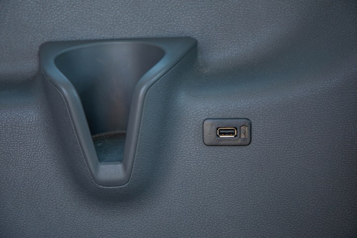 Car dashboard storage slot and USB port on a textured surface.