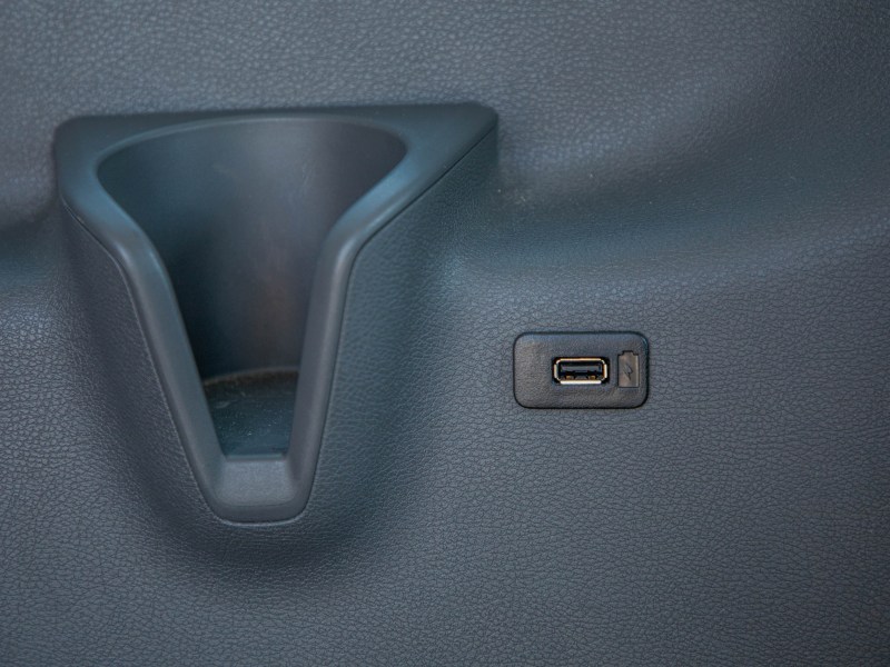 Car dashboard storage slot and USB port on a textured surface.