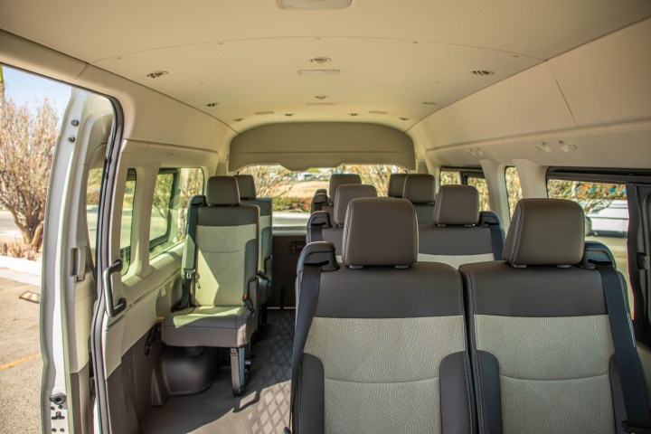 Interior of an empty passenger van with multiple rows of gray seats.